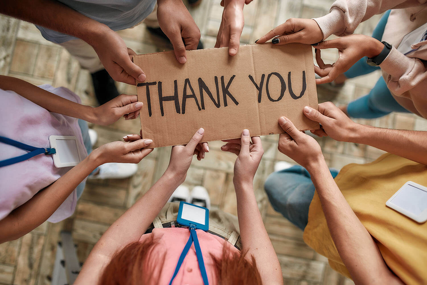 Close up of hands of a group of people holding a "Thank you" banner