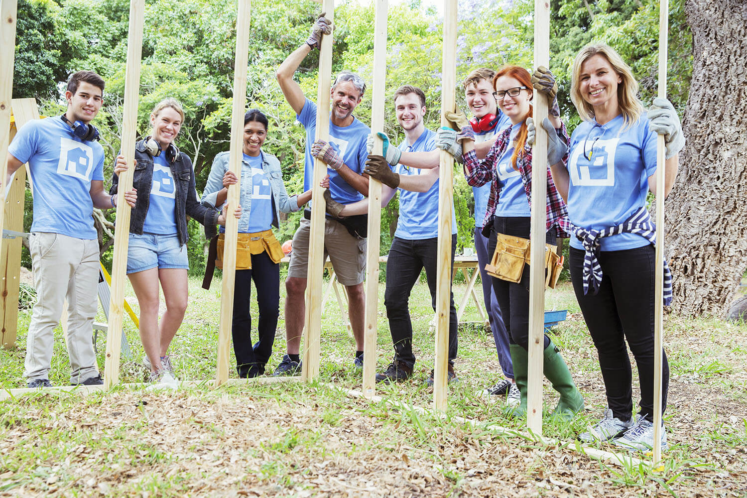 Volunteers posing in front of a house project in progress