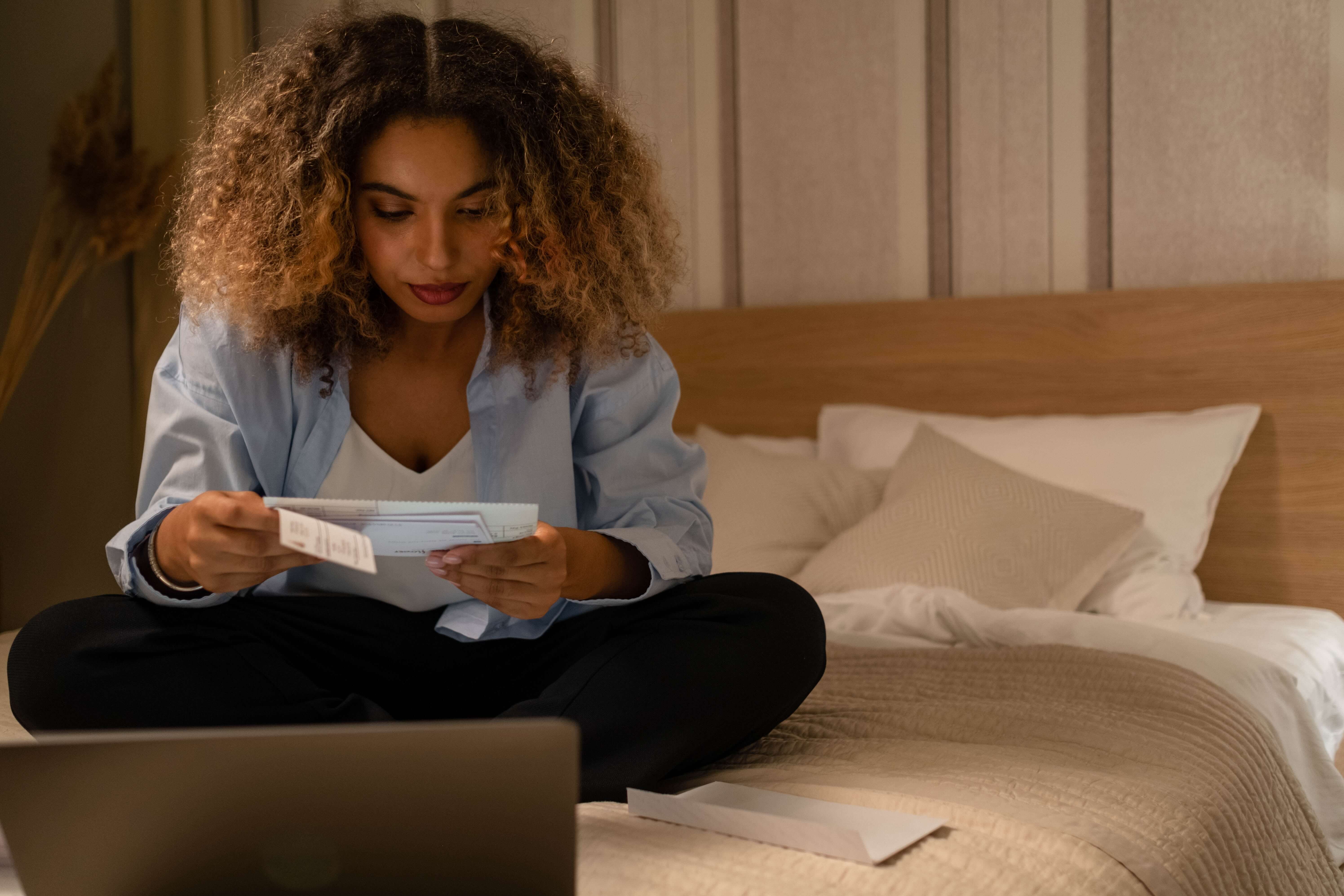 Woman sitting on her bed reading through mail