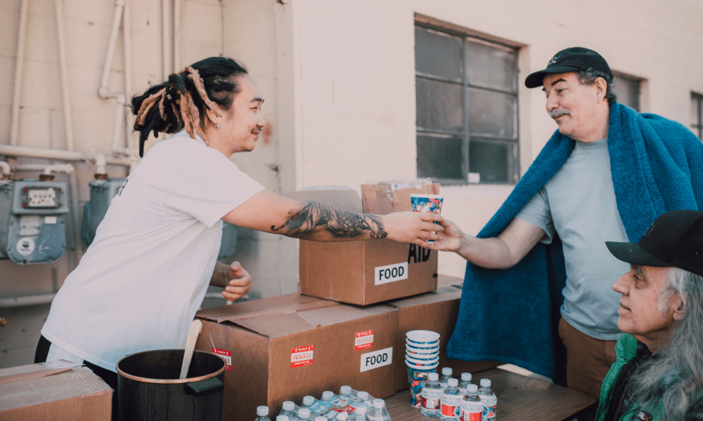 Young man giving food to two older men