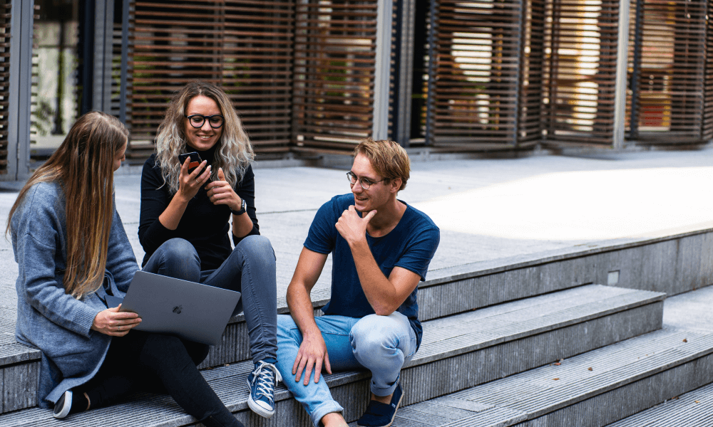 Three people sitting on the stairs doing online auctions