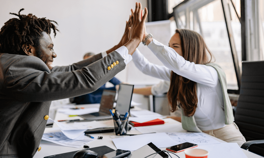 Coworkers doing a high five while celebrating a successful project