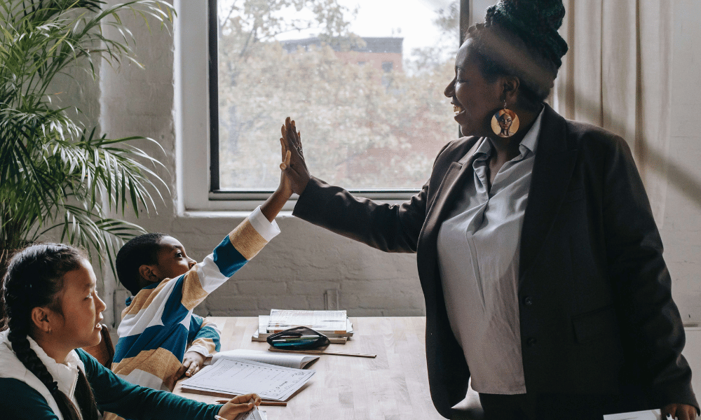 Volunteer tutor giving a high-five to students